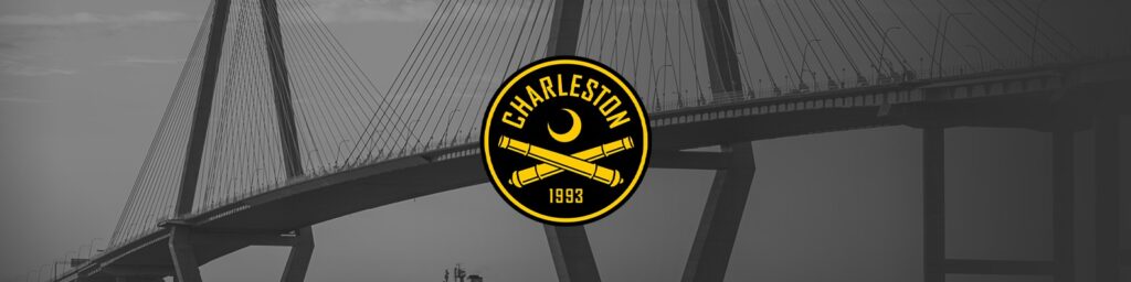 Black-and-white bridge backdrop with a bold yellow Charleston 1993 logo centered, featuring a crescent and two crossed cannons beneath it.