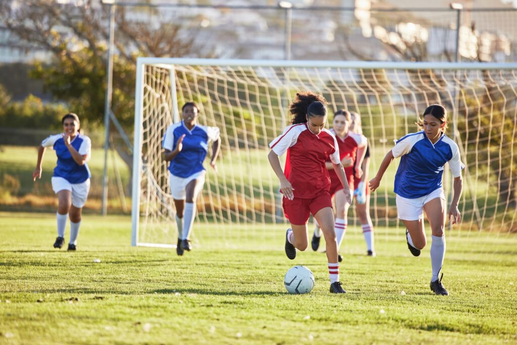 Sports team, girl soccer and kick ball on field in a tournament. Football, competition and athletic - Olly On The Ball Sports team, girl soccer and kick ball on field in a tournament. Football, competition and athletic