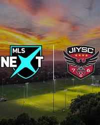 MLS NEXT logo and a JIYSC crest are displayed side by side on a well-lit soccer field at sunset.