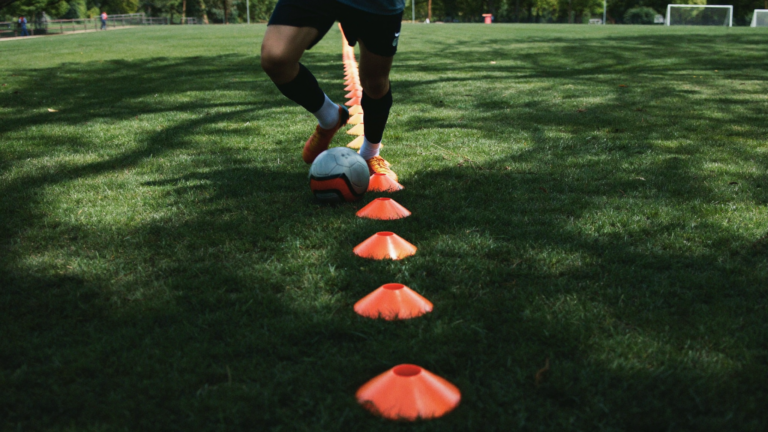 Close-up of a young soccer player dribbling through cones during footwork drills