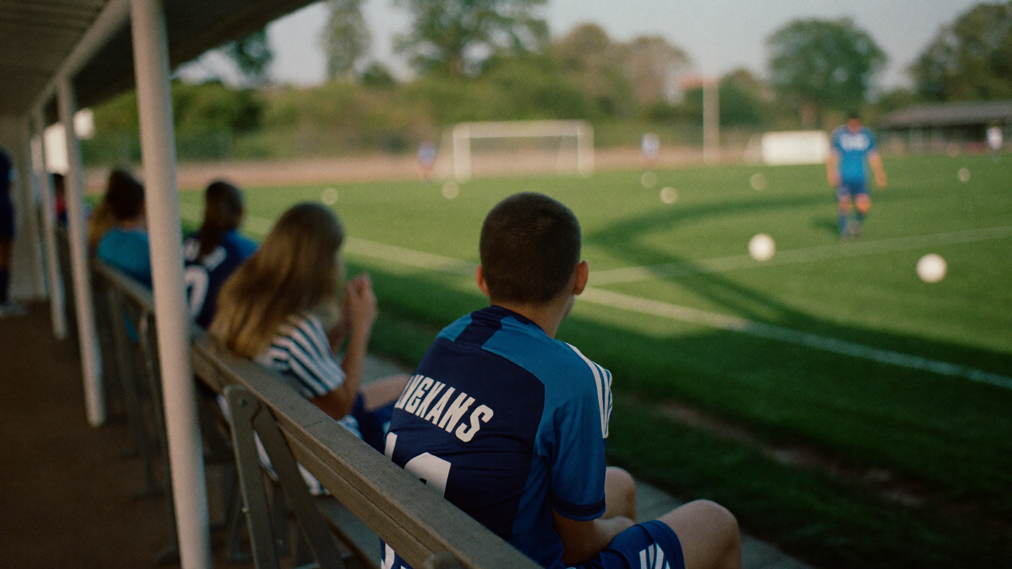 Young substitute soccer player waiting on the sideline bench to come into the match