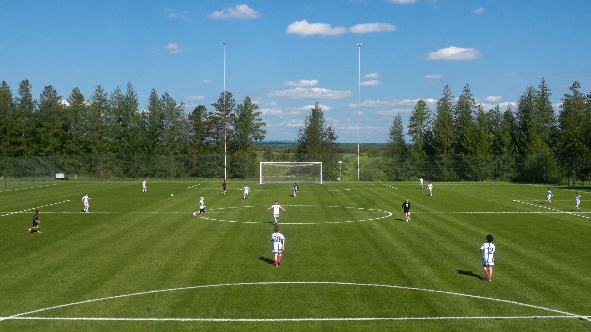 Players are spread across a grass field in formation during a youth soccer match, seen from a distance.