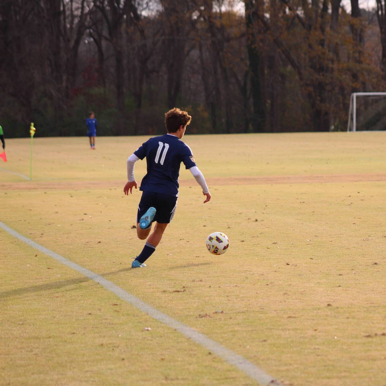 Player in a navy number 11 kit dribbling on a sunny field