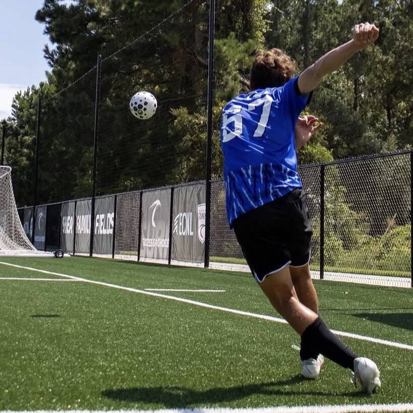 Player in a blue Surf kit striking the ball on a turf field