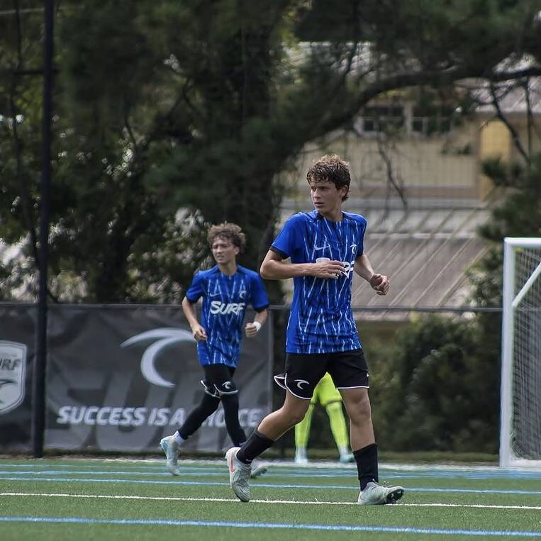 Two Surf players running on a turf field